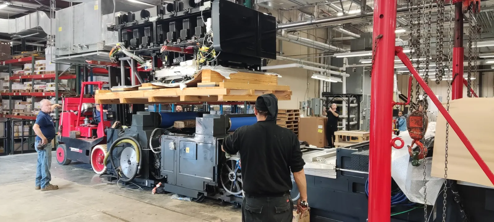 צוות טכני מטפל במכונת דפוס גדולה בתוך מפעל