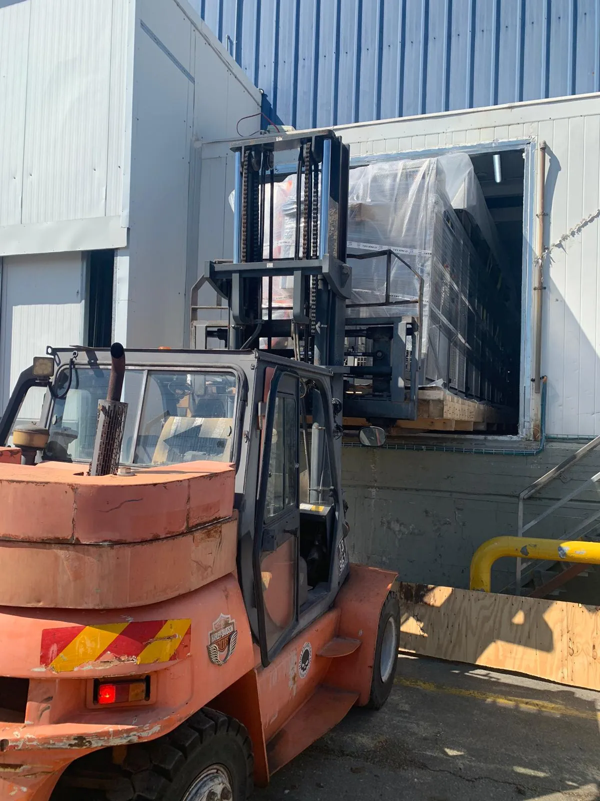 מלגזה מעבירה ציוד אריזה עטוף אל תוך מבנה מפעל