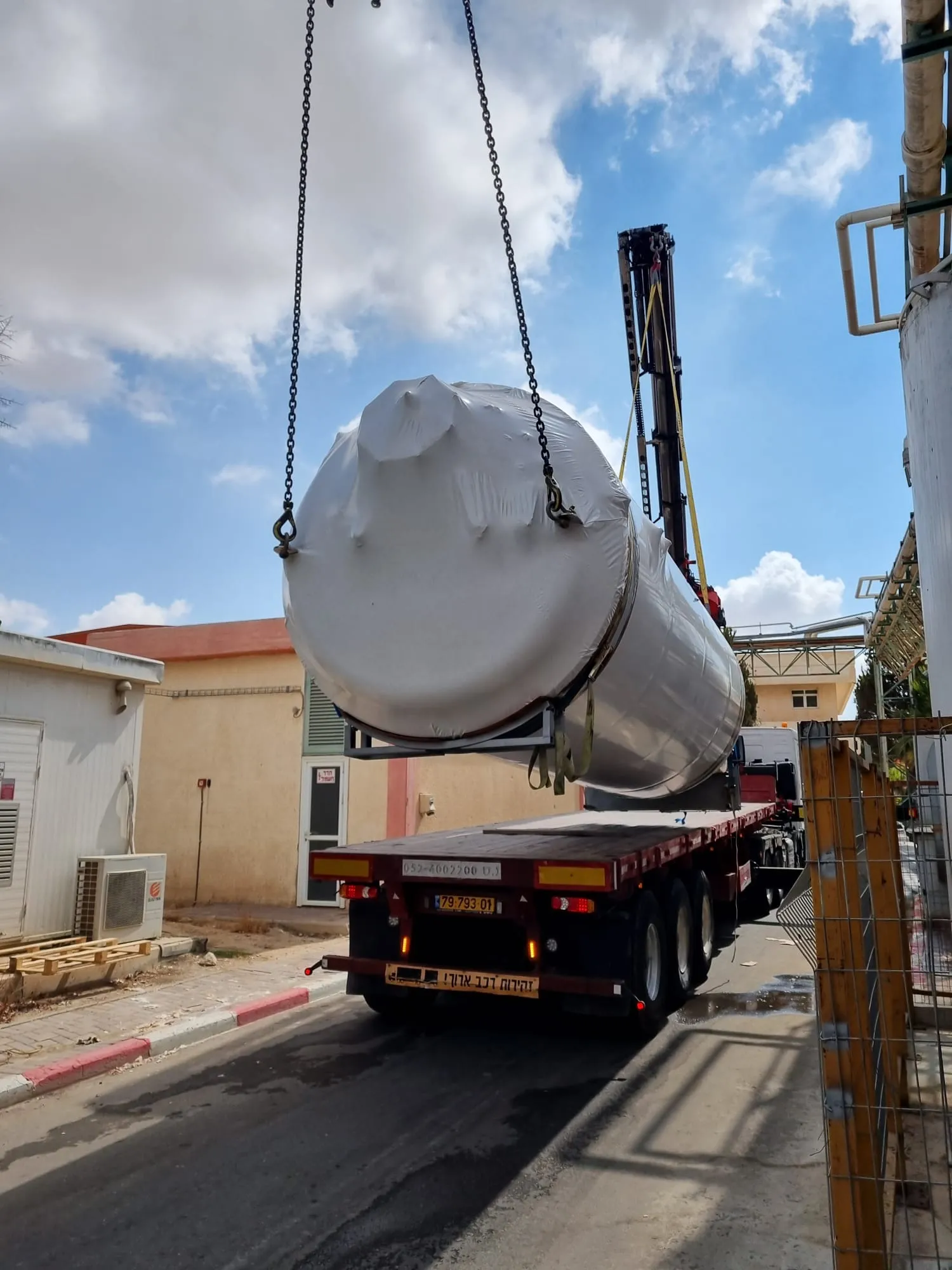 צוות מפעיל ריגינג עם שרשראות במרחב של מפעל תעשייתי